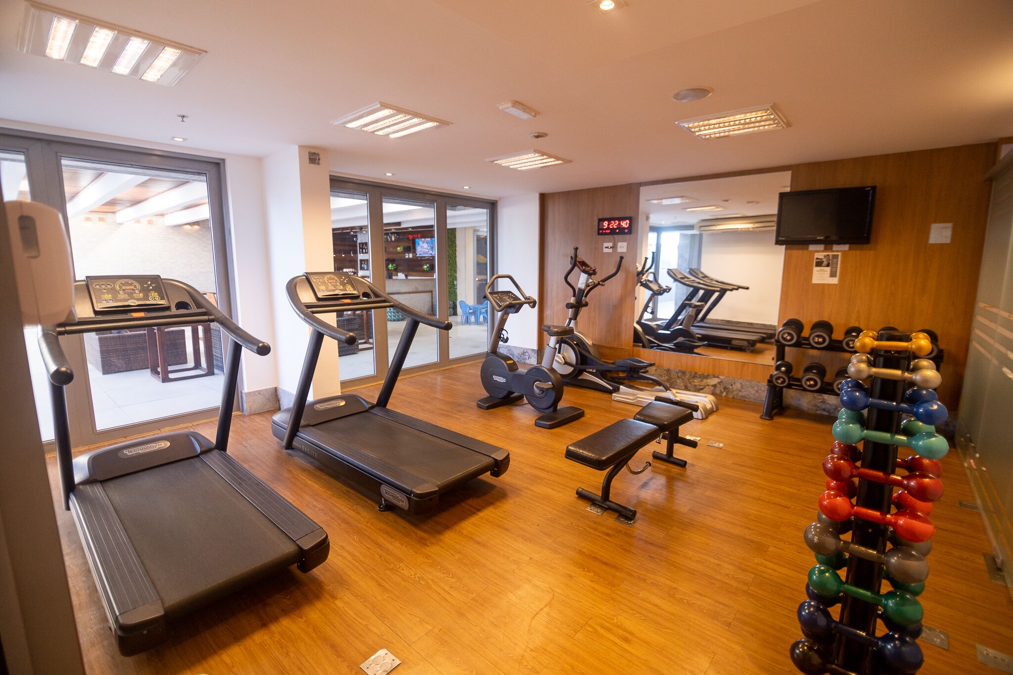 Une salle de sport équipée de tapis de course, de vélos d’appartement, d’un banc de musculation et d’un porte-haltères.