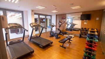 Une salle de sport équipée de tapis de course, de vélos d’appartement, d’un banc de musculation et d’un porte-haltères.