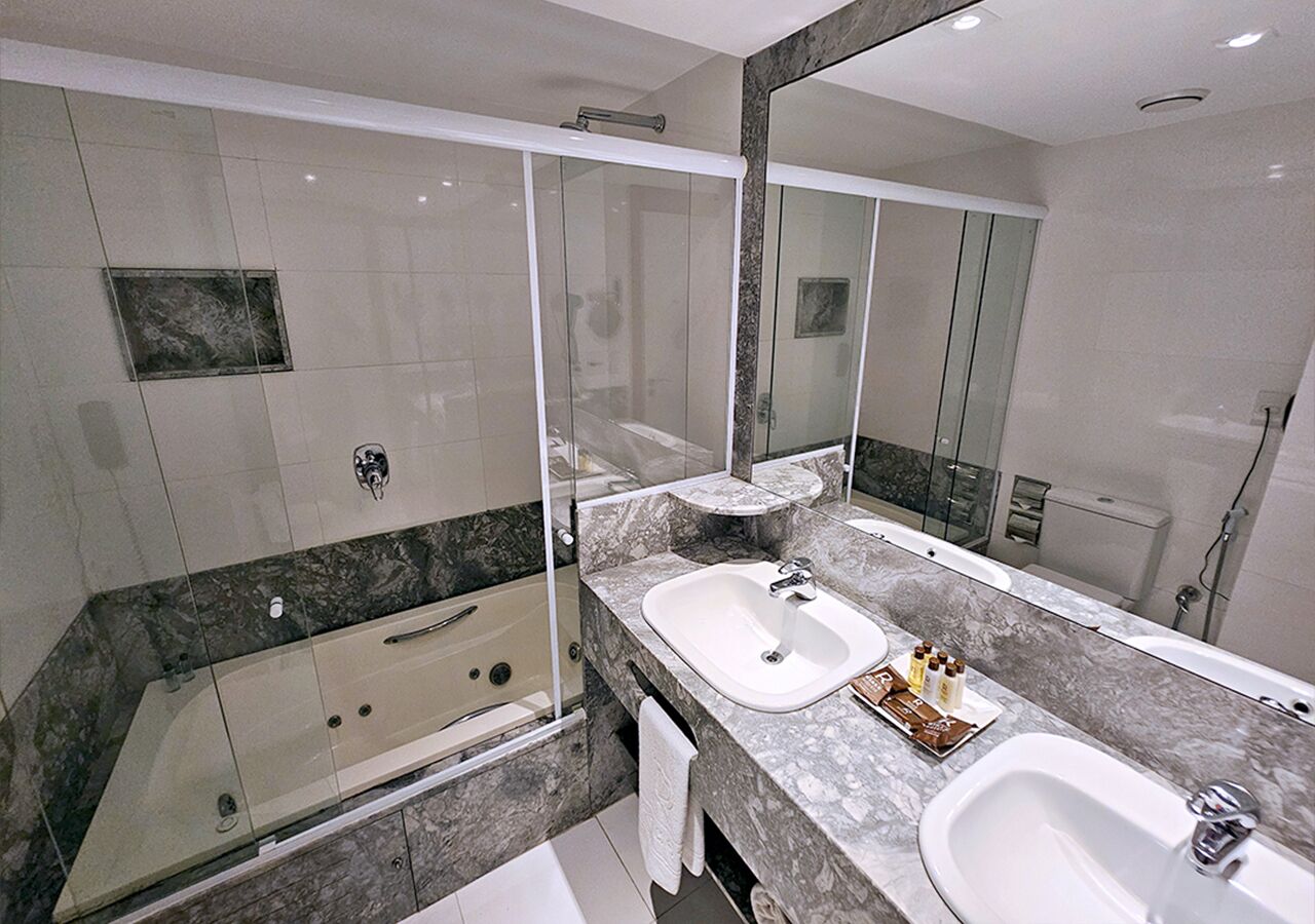 A modern bathroom with a glass-enclosed shower, two sinks, and a large mirror.