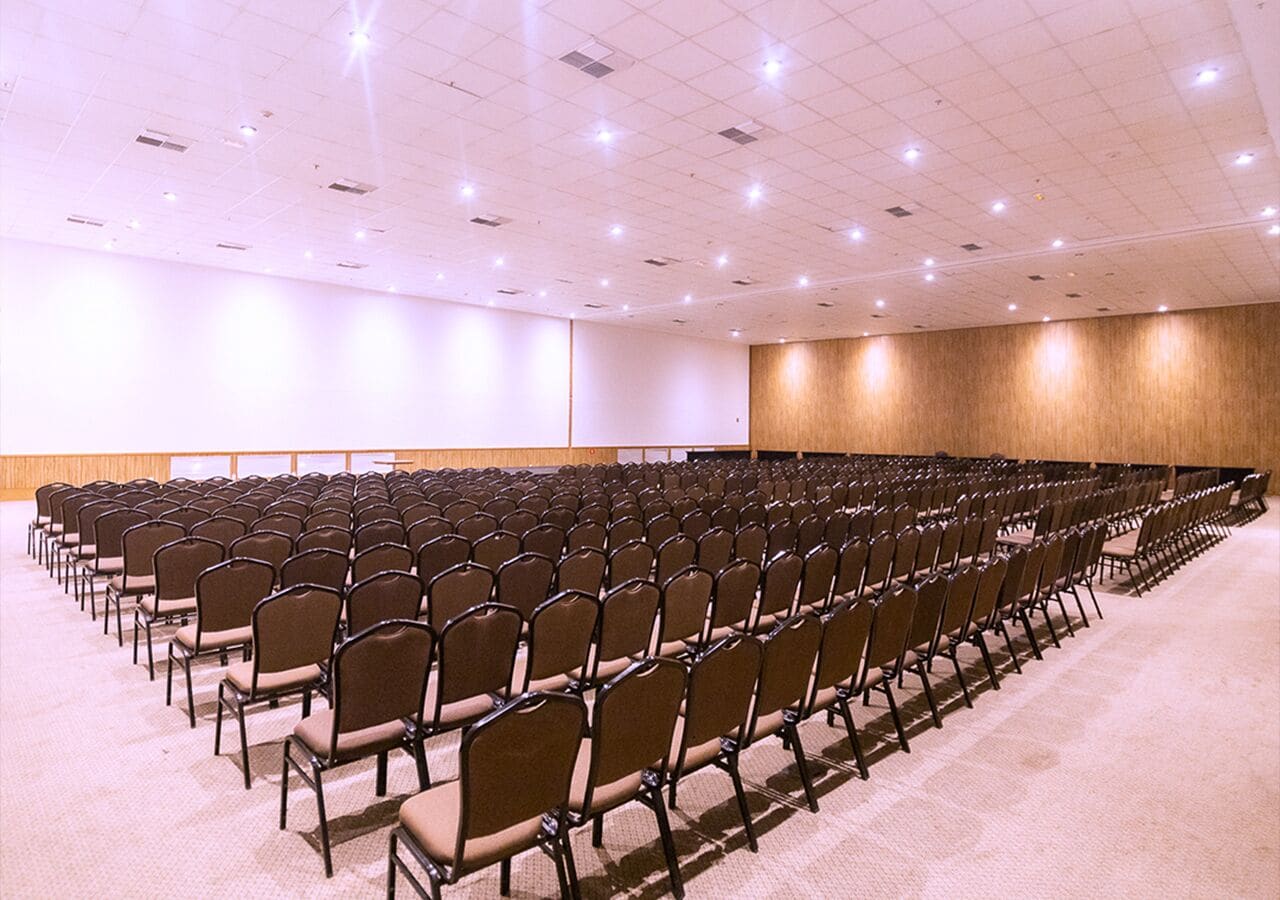 A conference room with rows of chairs, a large screen, and a wooden accent wall.