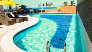 A swimming pool with a curved edge, lounge chairs, and umbrellas.