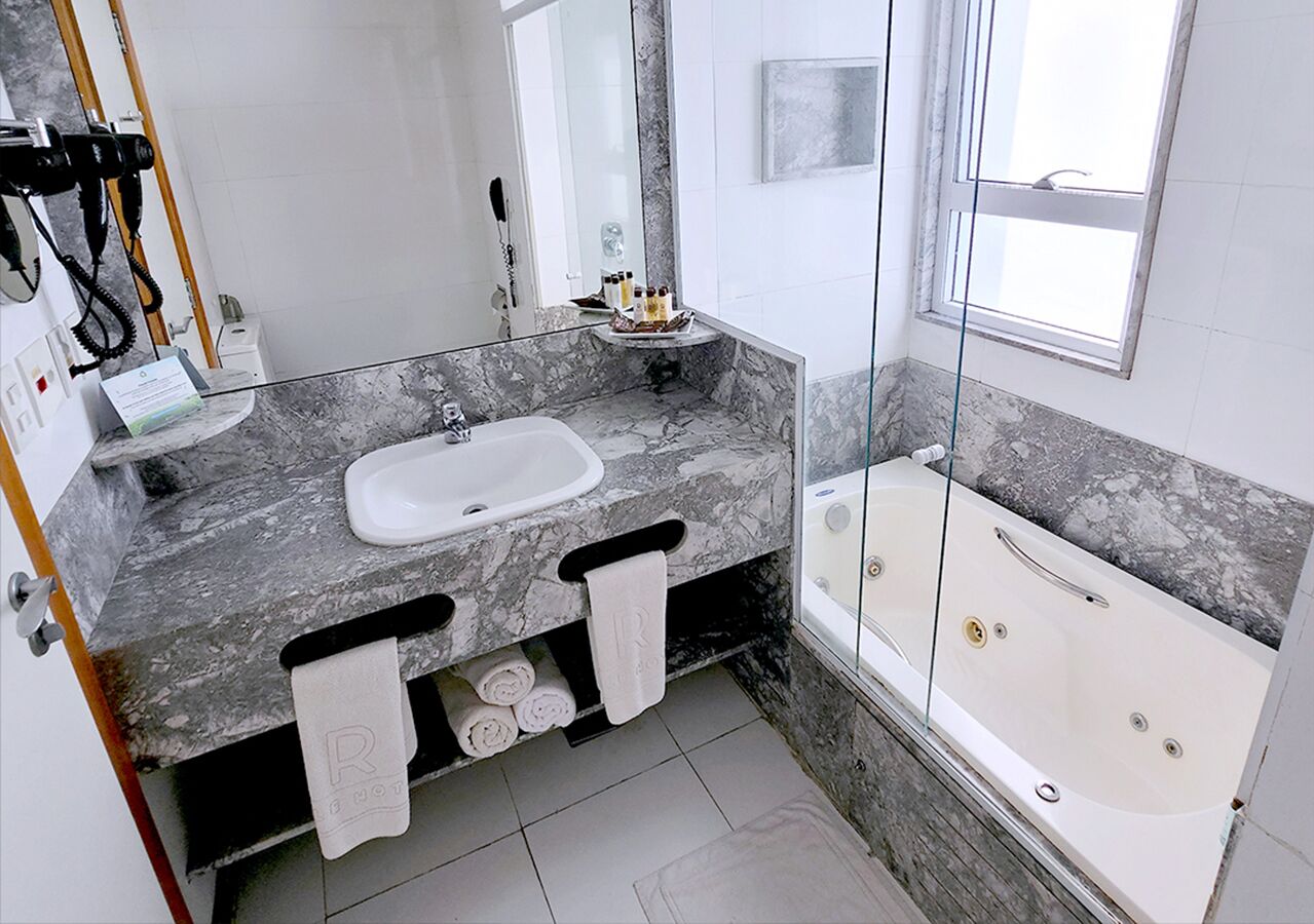 Un baño moderno con encimera de mármol, un lavamanos, una bañera y una ducha con mampara de vidrio.