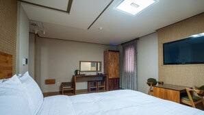 A hotel room with a bed, desk, chair, and a TV mounted on the wall. - Hotel Maple (Jeju City)