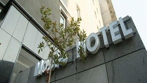 A hotel entrance with a modern facade, large windows, and a sign that reads "HOTEL". - Hotel Maple (Jeju City)