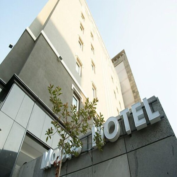 A hotel entrance with a modern facade, large windows, and a sign that reads "HOTEL".