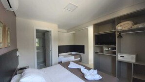 Habitación de hotel con cama, televisor, armario y baño.