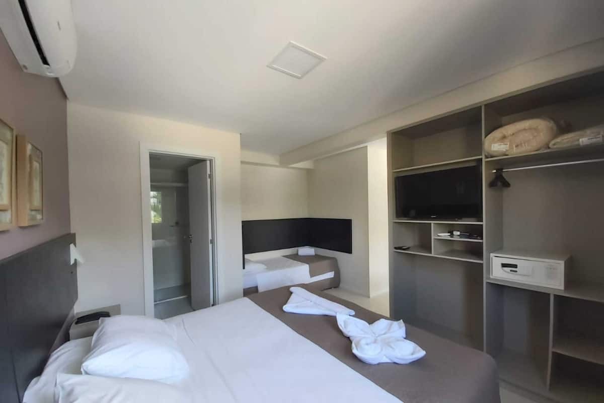 Habitación de hotel con cama, televisor, armario y baño.