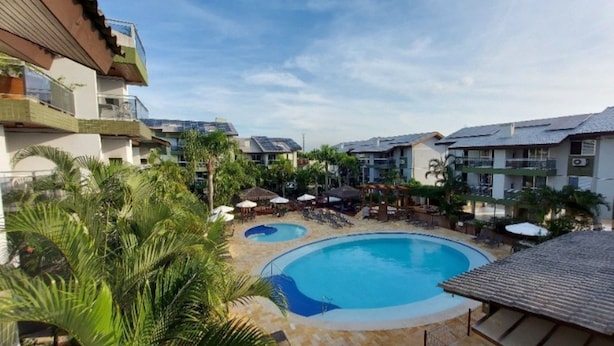 Un resort con piscina central, varias zonas de descanso y diversas construcciones con balcones.