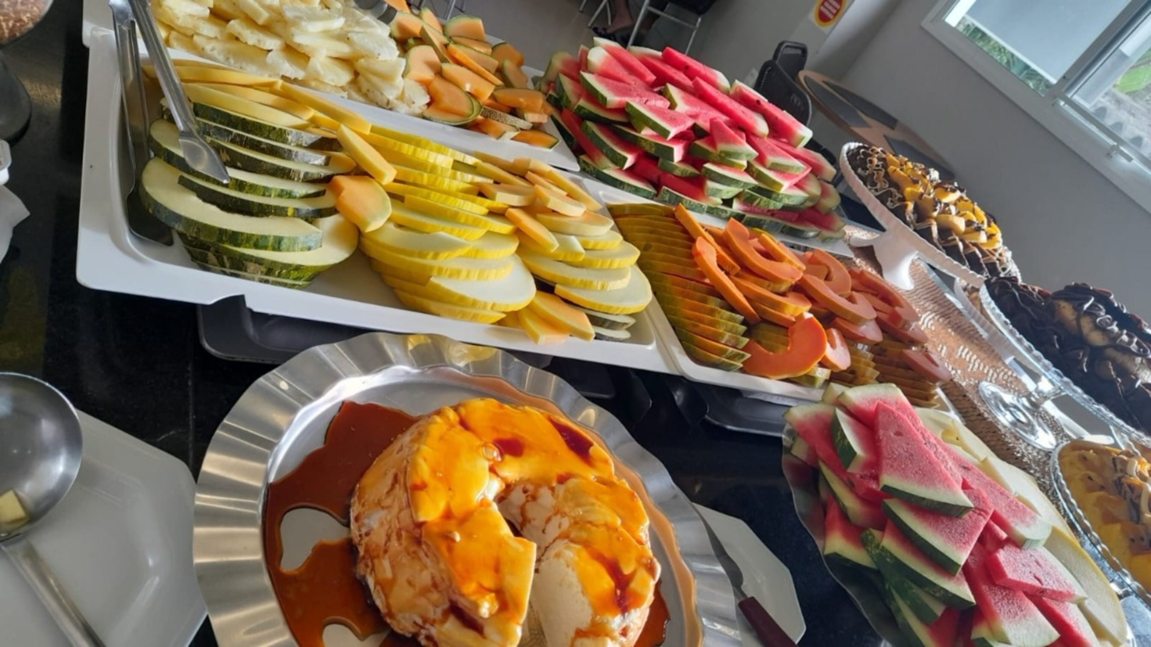 A buffet with various fruits and a dessert.