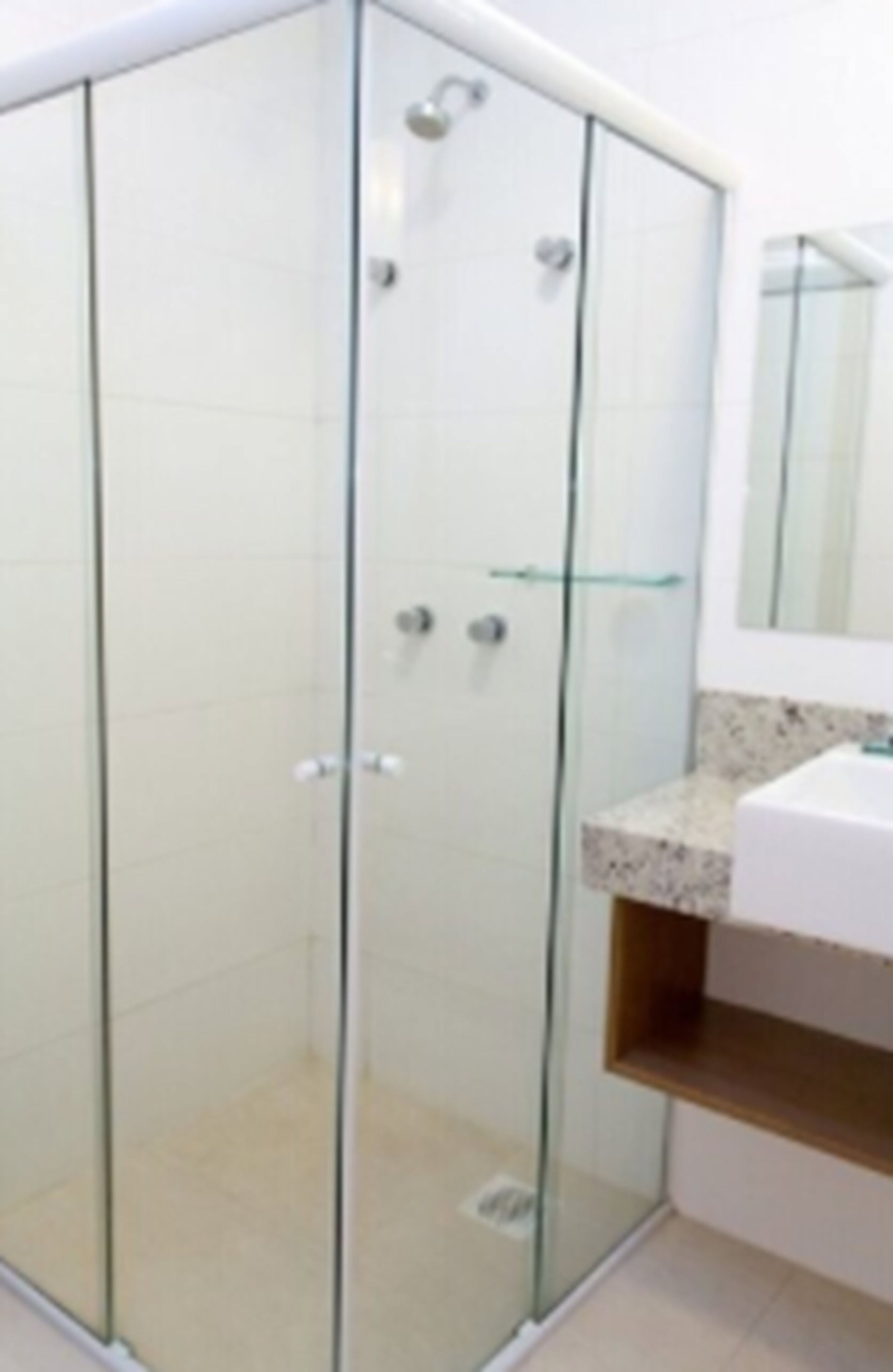 A modern bathroom with a glass-enclosed shower, a white sink, and a mirror above the sink.