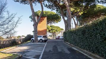 Un espace de stationnement avec des voitures, des arbres et un bâtiment en briques.