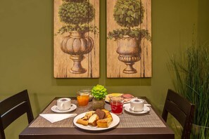 A dining table with a plate of food, a coffee cup, a glass of orange juice, and a vase with a plant. - Hotel Roma Sud (Frascati)