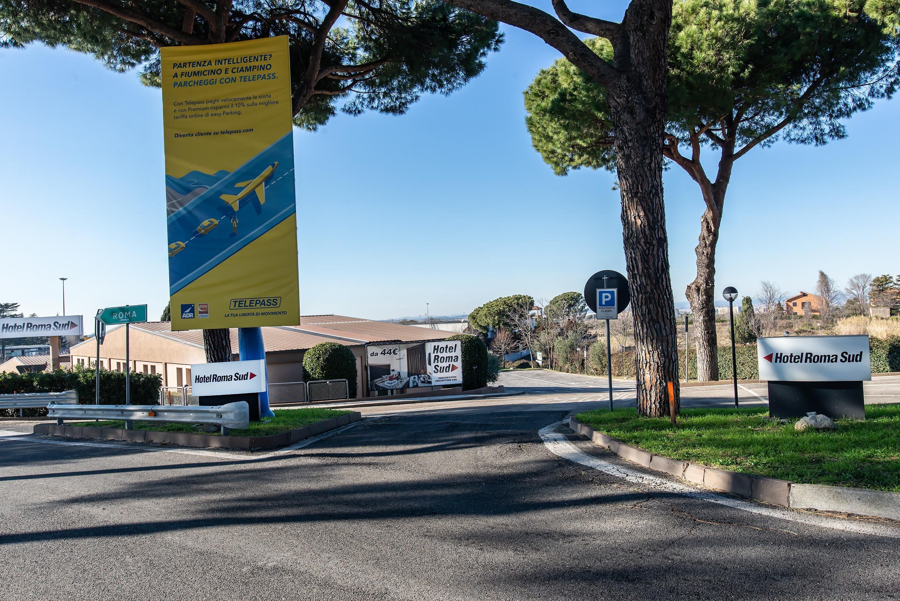 A road leading to Hotel Roma Sud with a banner advertising a parking service.