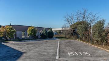A parking lot with a 'BUS' sign, a building with a flat roof, and some trees.
