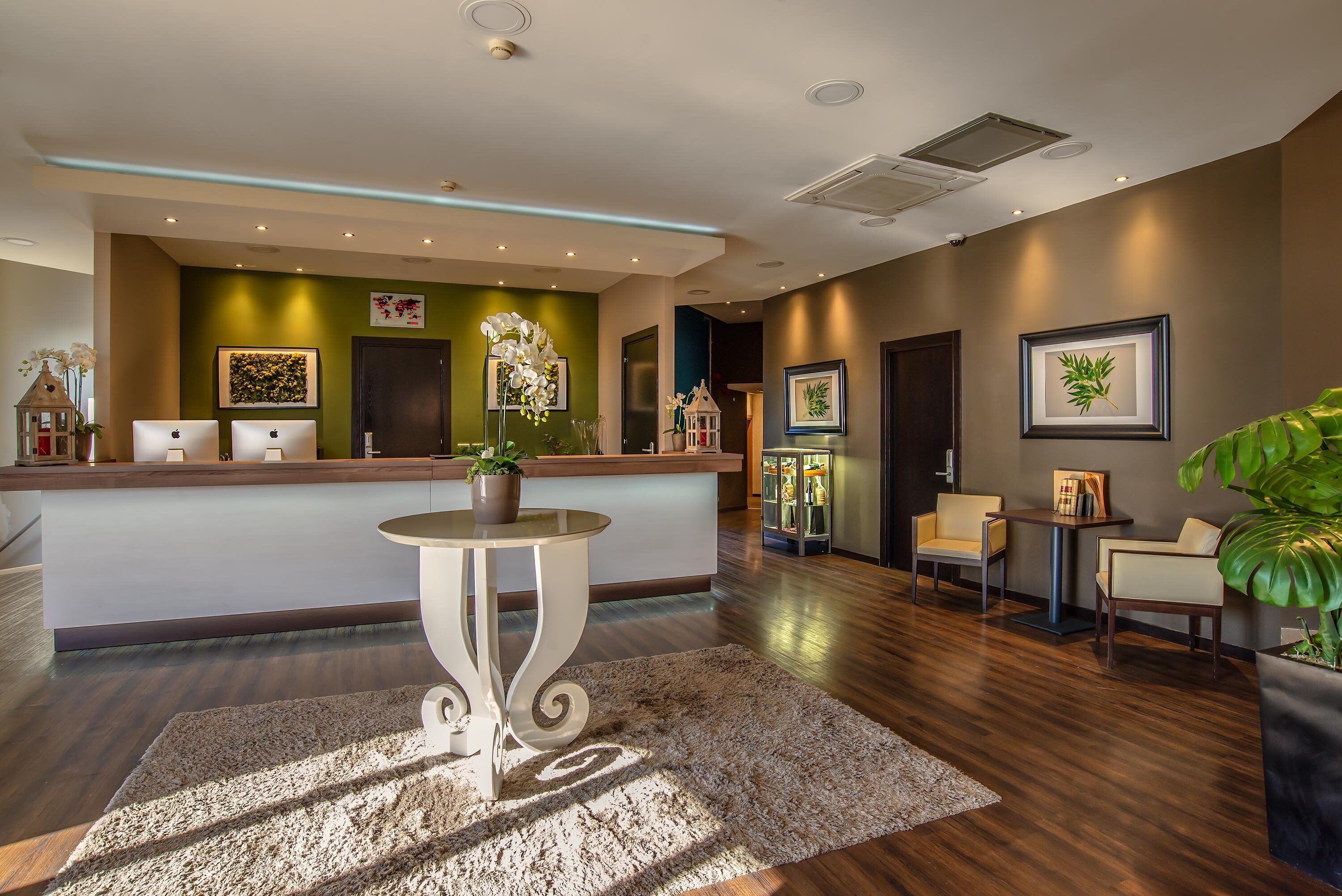 A reception area with a counter, chairs, a small table with a plant, and framed artwork on the walls.