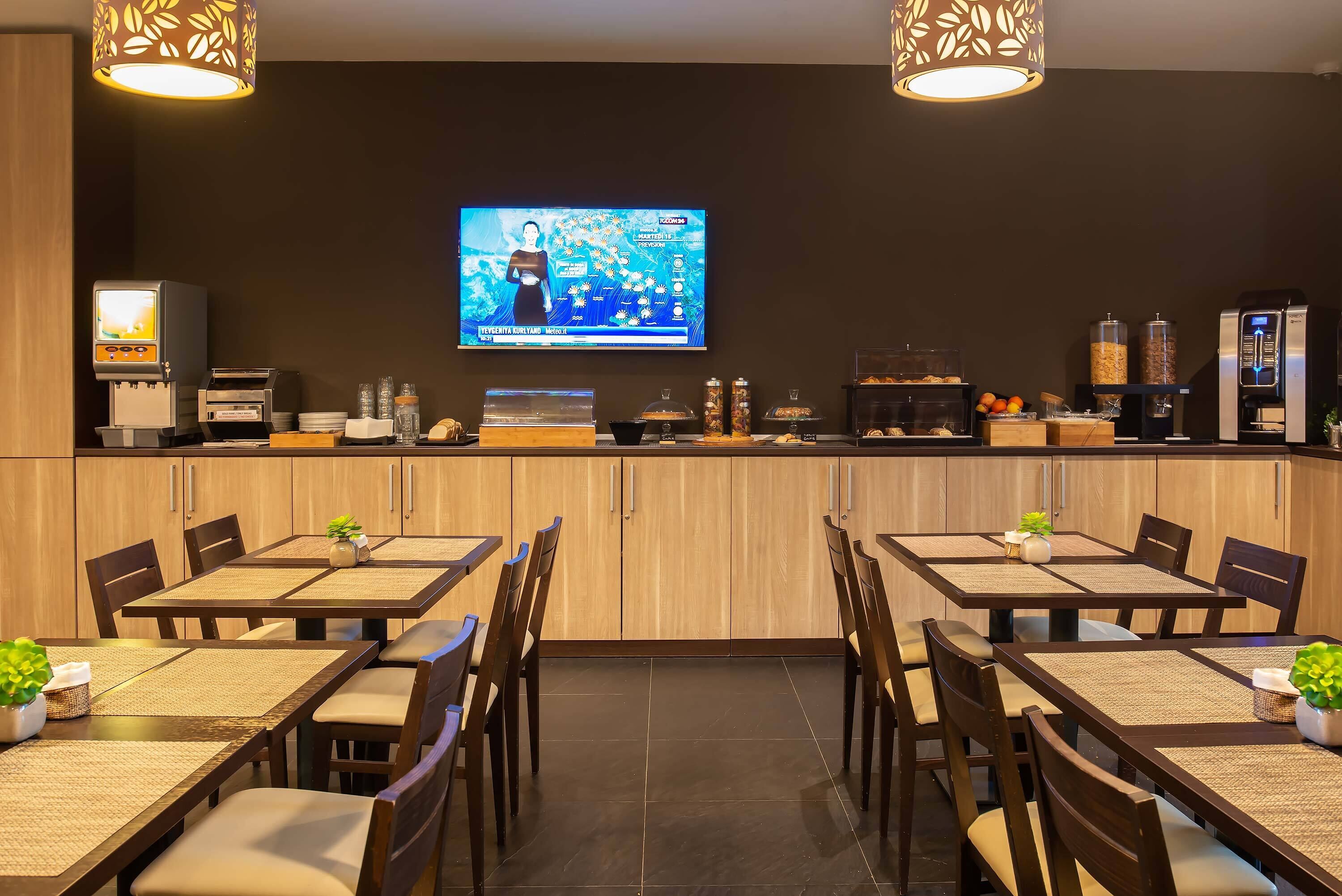 Un restaurant doté d’un téléviseur diffusant un programme d’information, de meubles en bois et d’un comptoir où sont exposés divers produits alimentaires, ainsi qu’une machine à café.