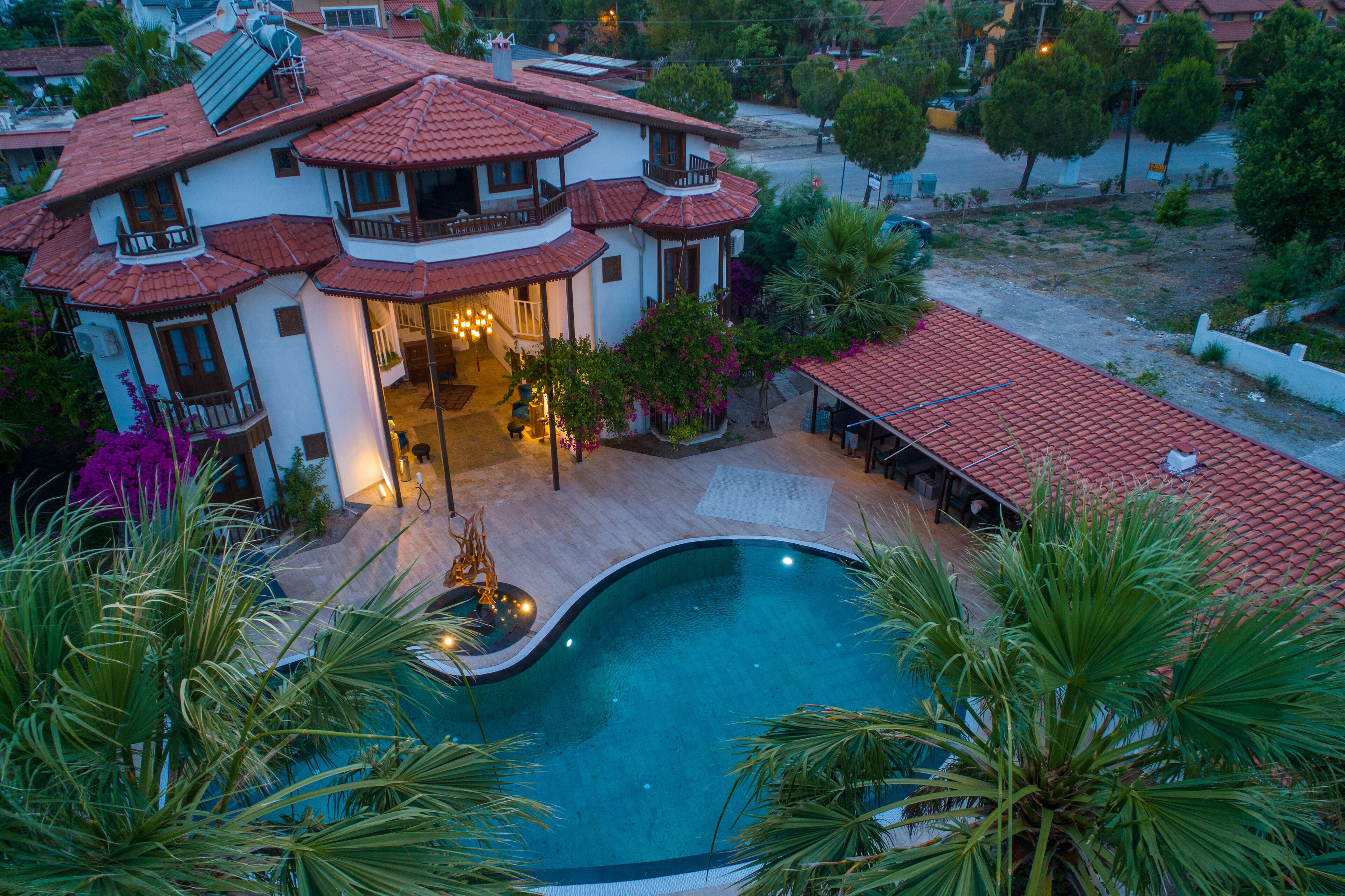 Una casa grande con piscina, varios balcones y un jardín bien cuidado.