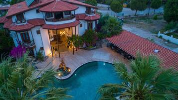 Una casa grande con piscina, varios balcones y un jardín bien cuidado.