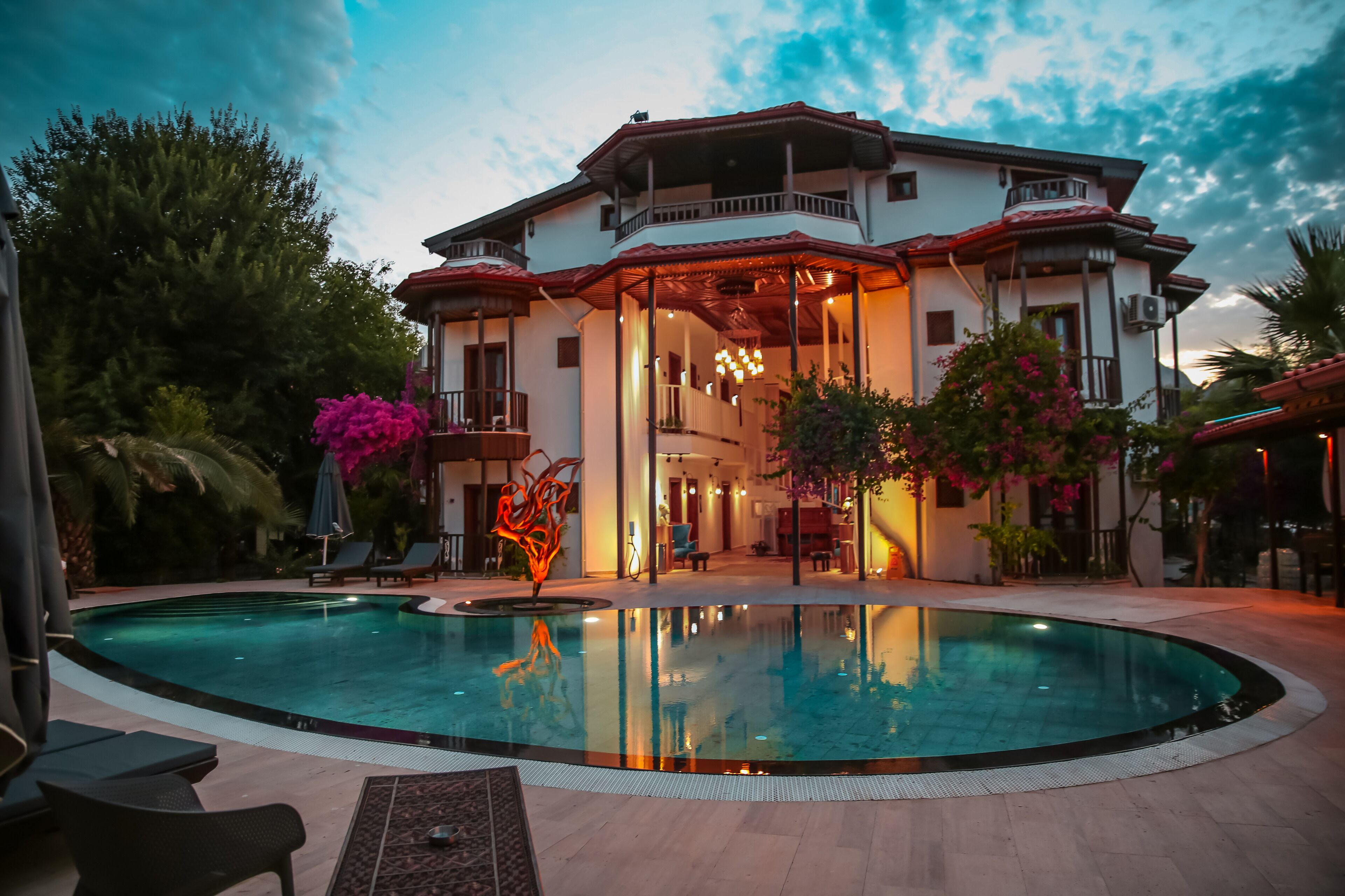Un edificio grande con piscina, zona de estar al aire libre y un espacio cubierto con iluminación.