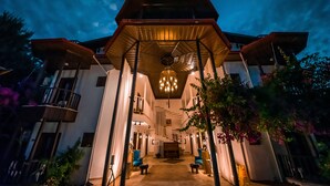 A modern building with a central staircase, multiple balconies, and a covered entrance area with seating. - Murat Paşa Konağı Boutique Hotel (Ortaca)