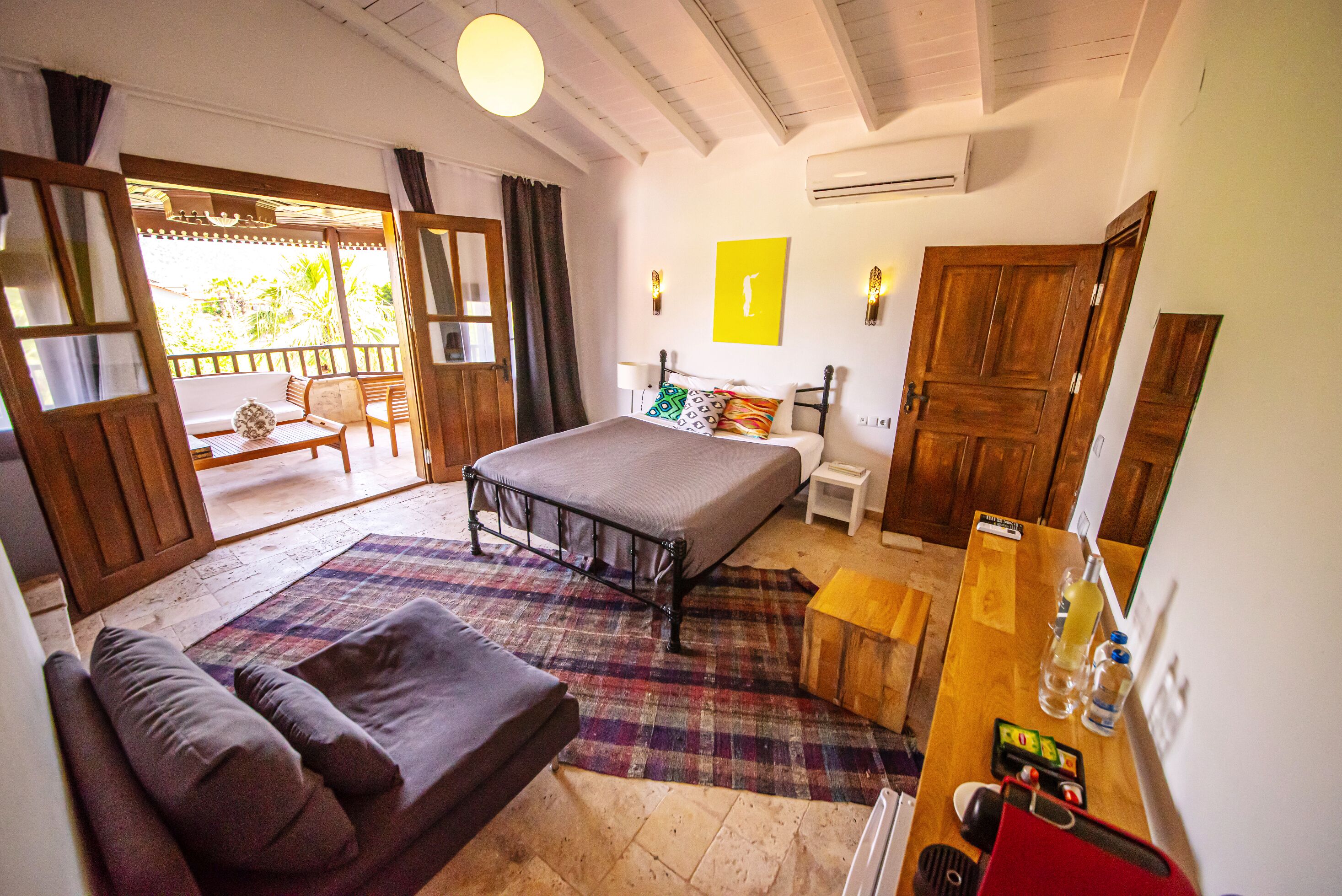 A room with a bed, a sofa, a small table, and a wooden door.