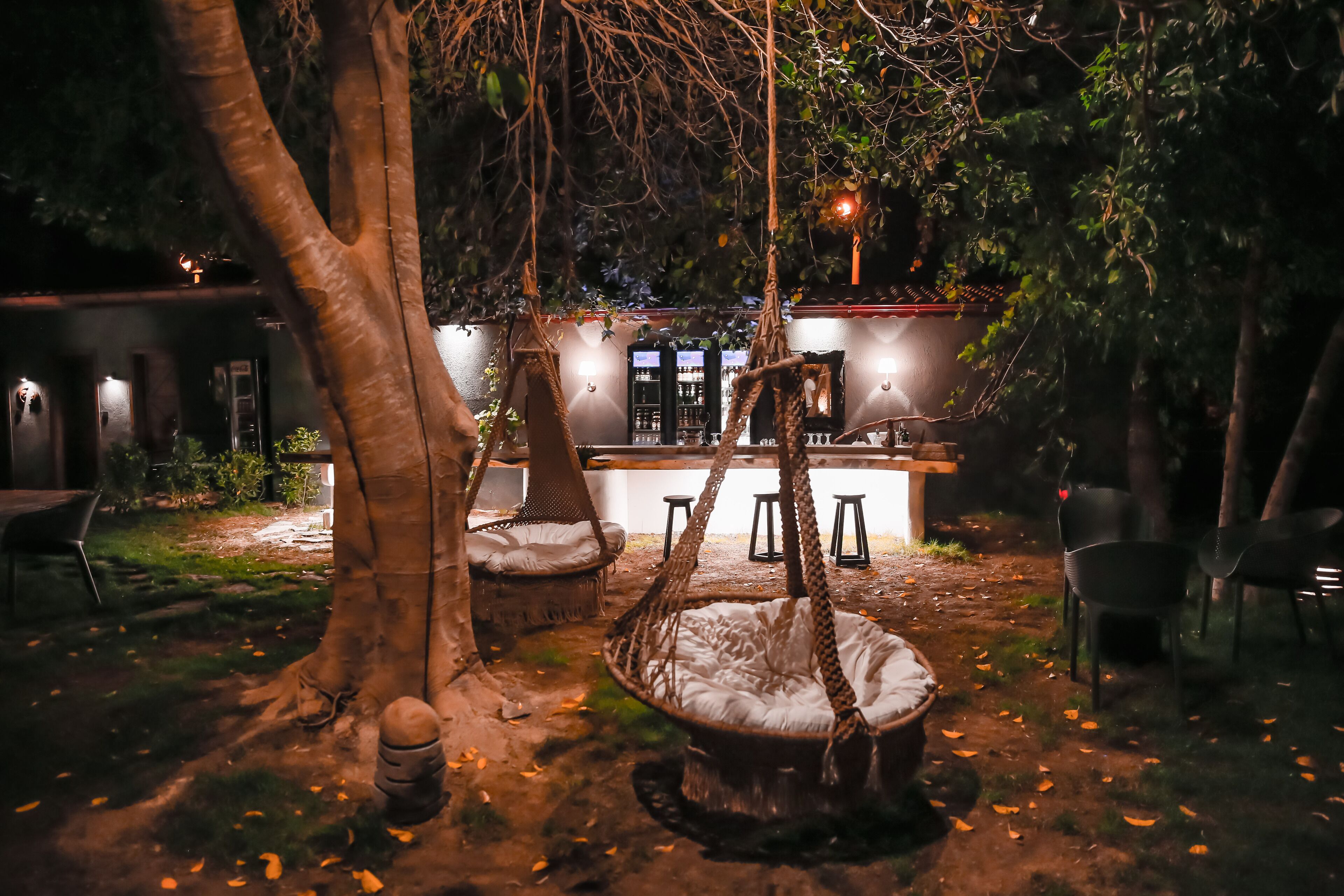 Uma área de estar ao ar livre com cadeiras suspensas e um bar.