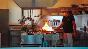 A chef cooking with a flame on a stove in a modern kitchen. - Murat Paşa Konağı Boutique Hotel (Ortaca)