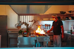 Un chef cocinando a llama viva sobre un fogón en una cocina moderna.