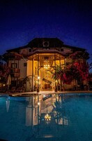 Un hotel con piscina, mobiliario exterior y una entrada bien iluminada.