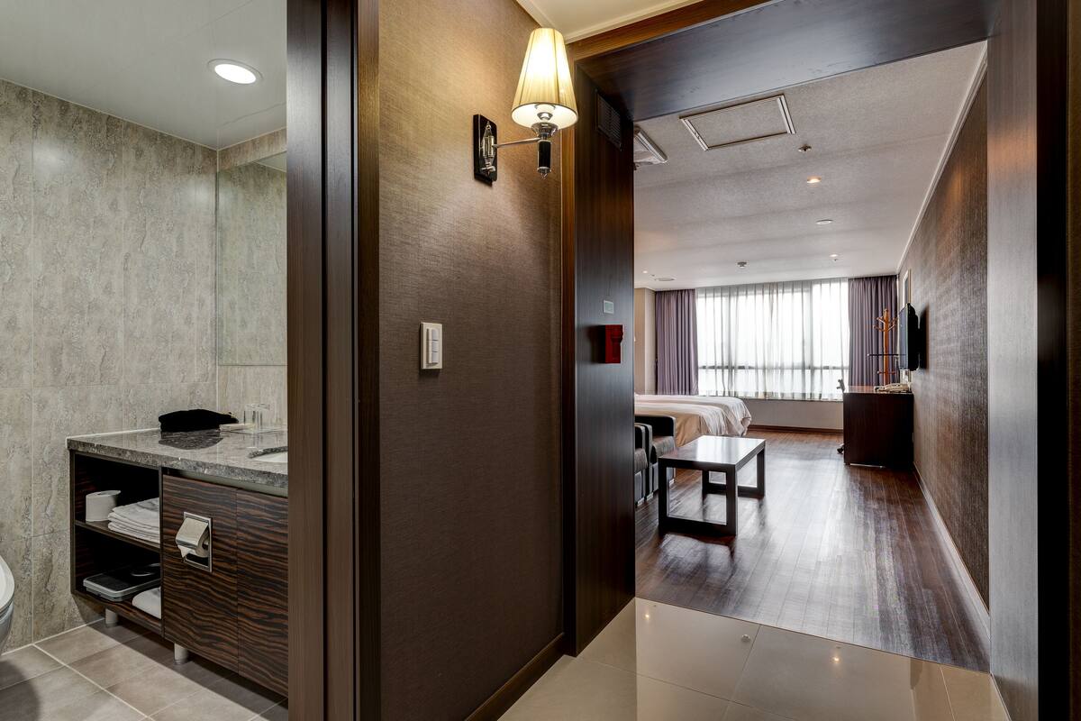 Una habitación de hotel moderna con baño, zona de comedor y vistas a la ciudad.