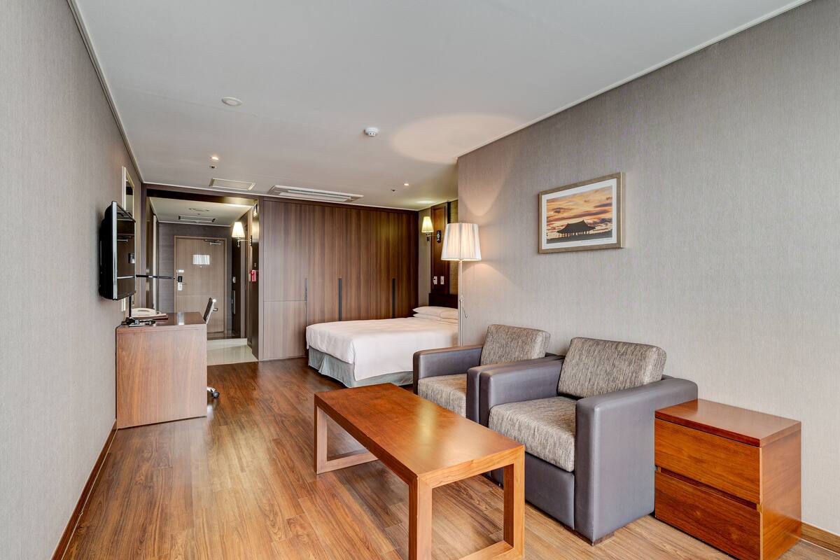 Una habitación de hotel con cama, sofá, escritorio y lámpara.