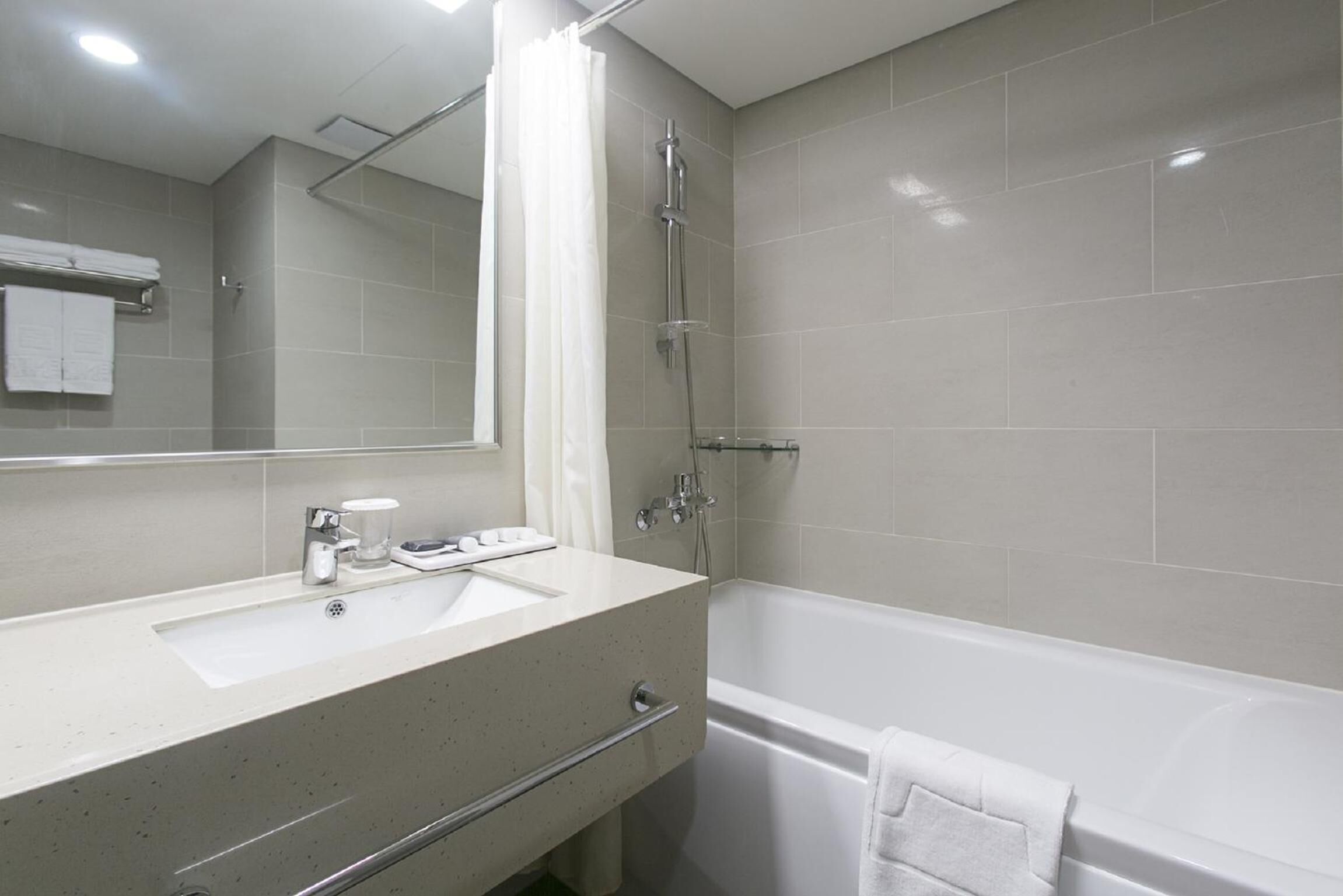 A modern bathroom with a sink, mirror, shower, and bathtub.
