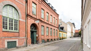 En kullerstensgata kantad av historiska byggnader i rött tegel, inklusive en byggnad med en grön dörr och en skylt med texten "WINSTRUPF".