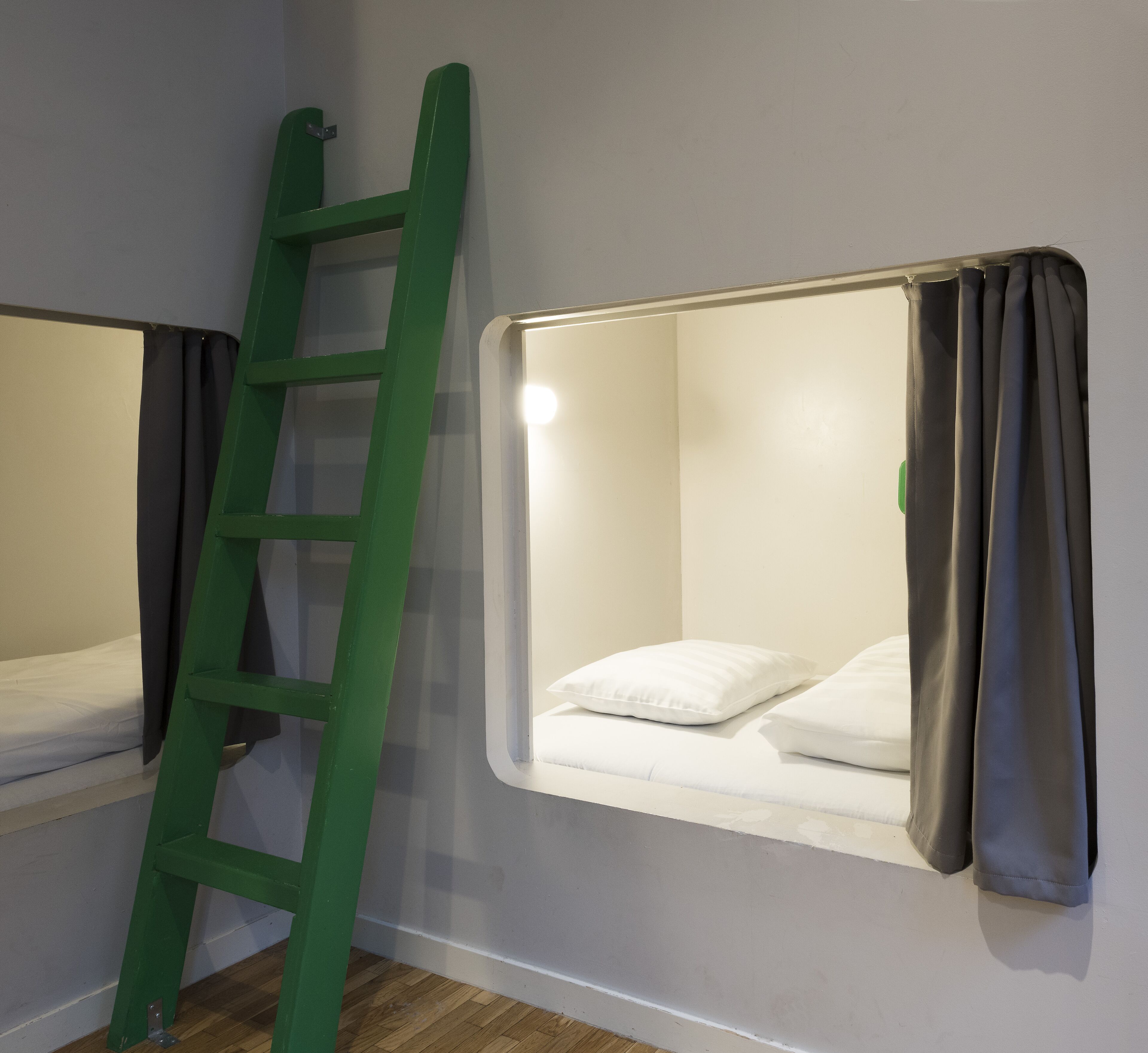 A bunk bed with a ladder, a window with curtains, and a white pillow.