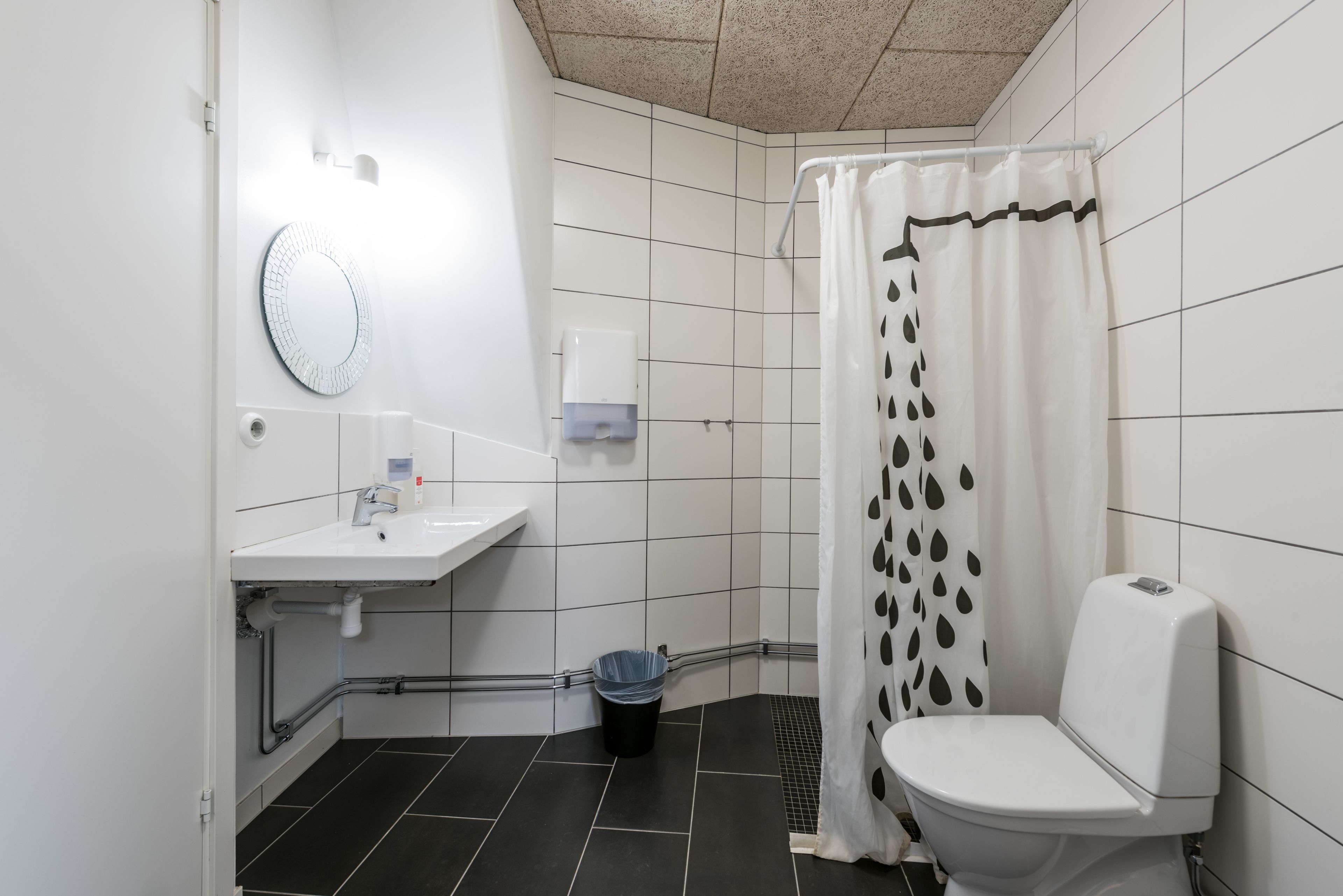 Een compacte, schone badkamer met een wit wastafelmeubel, spiegel, toilet en douchegordijn.