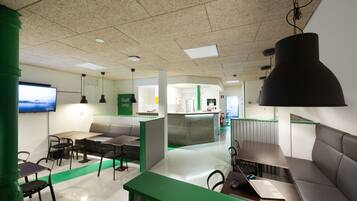 A modern office space with green partitions, a reception area, and a kitchenette.