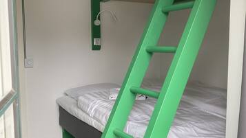 A bunk bed with a green ladder, a white wall, and a window.