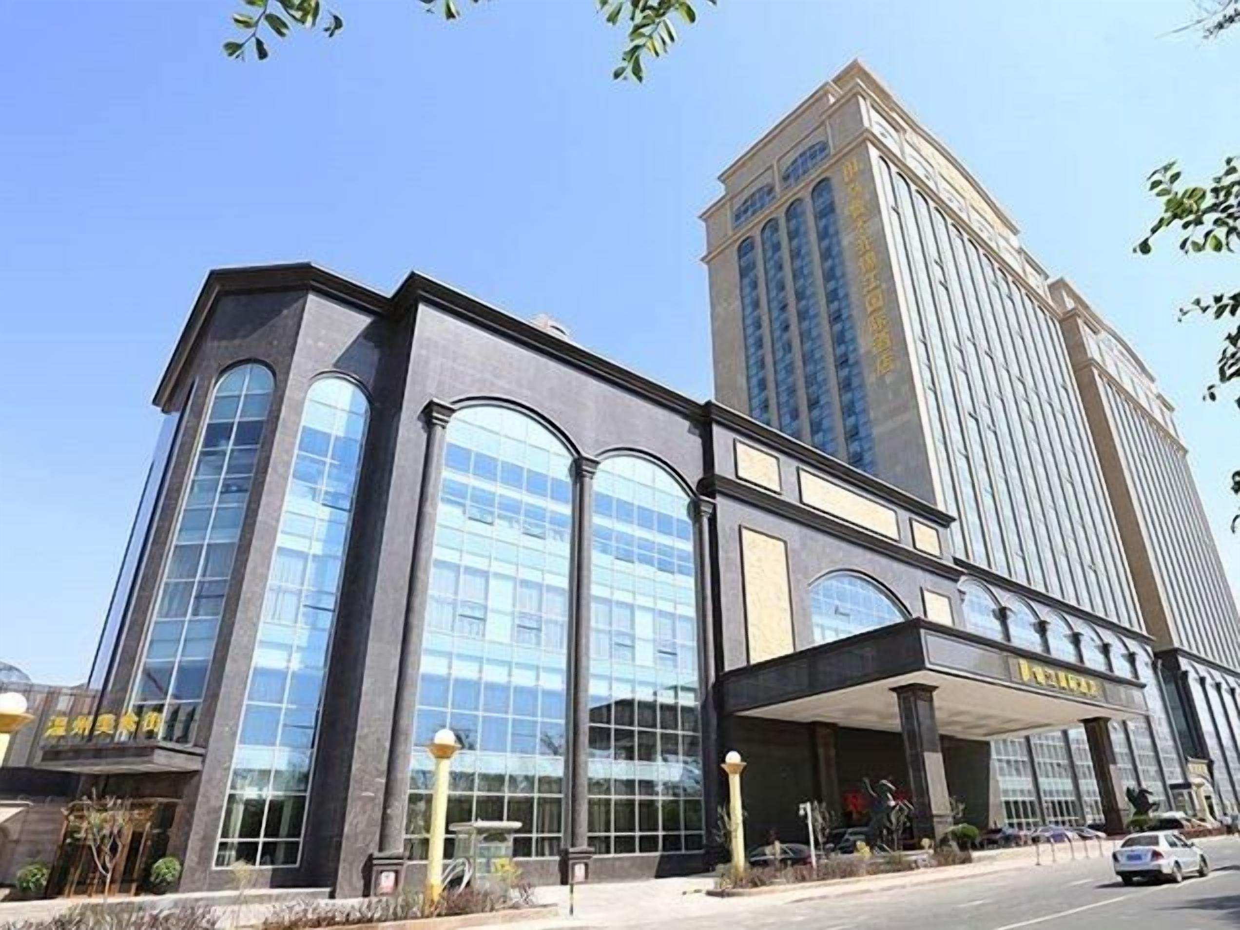 Un hotel moderno con una entrada destacada, ventanas amplias y un edificio alto contiguo.