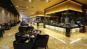 Een ruime hotellobby met marmeren vloeren, modern meubilair en een bar in het midden.