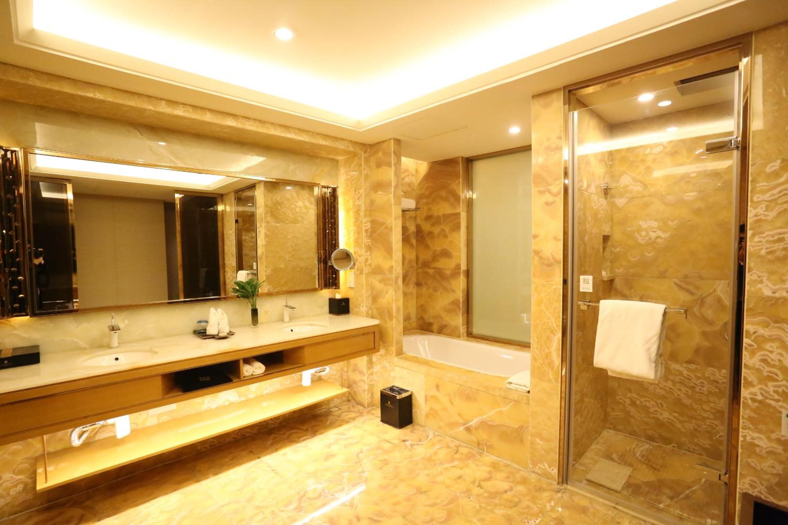 A modern bathroom with a large mirror, a bathtub, and a glass-enclosed shower.