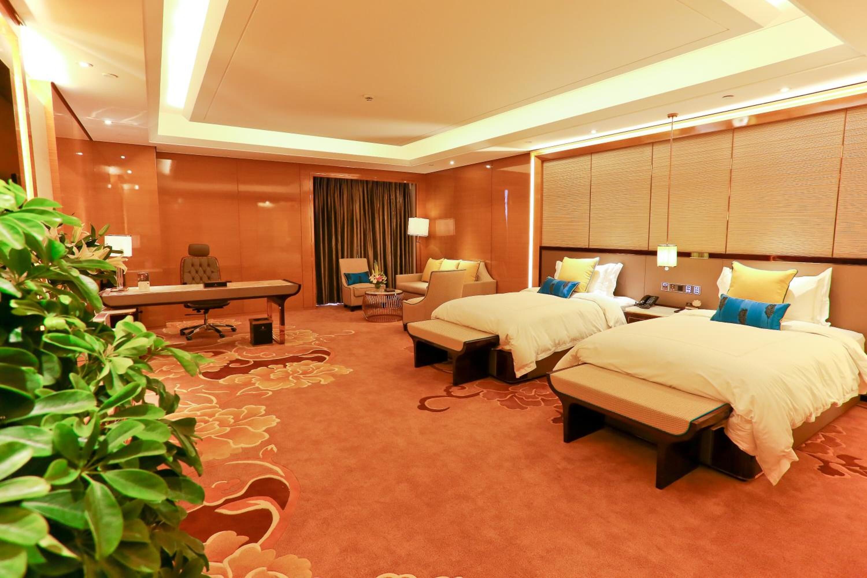 Une chambre d’hôtel avec deux lits, un bureau, une chaise, un canapé et une grande fenêtre avec des rideaux.