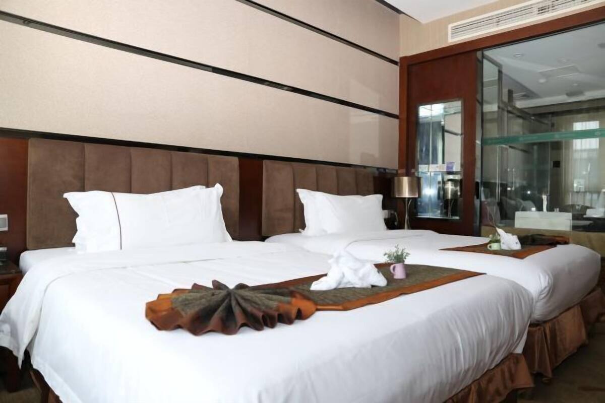 Een hotelkamer met een groot bed, een nachtkastje, een lamp en een grote spiegel.