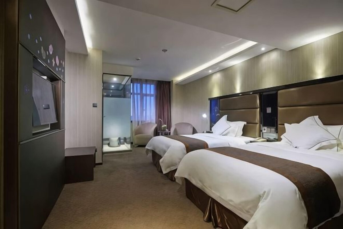 A hotel room with two beds, a desk, and a chair.