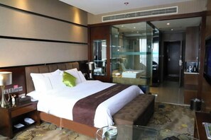 A hotel room with a large bed, a glass partition, a television, and a small table. - Liwan International Hotel (Chengdu)