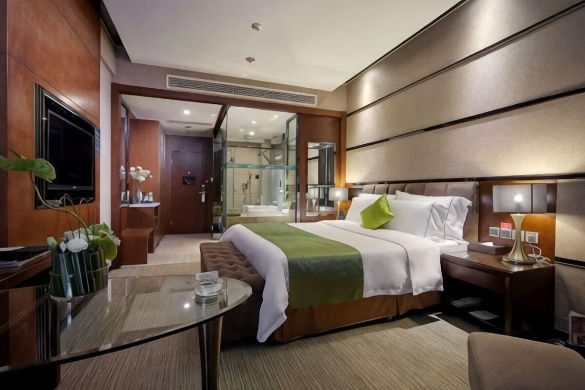 A hotel room with a large bed, bedside table, and a TV.