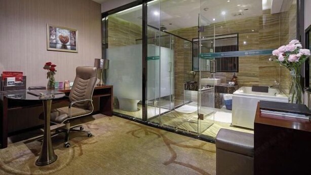 Una habitación de hotel moderna con un separador de vidrio que divide la zona de estar del baño.
