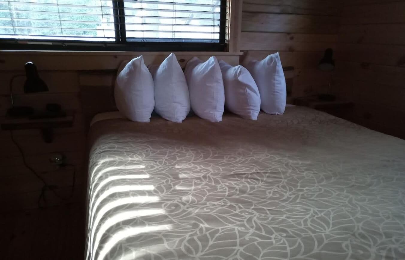 Un letto con una coperta a motivi e numerosi cuscini.