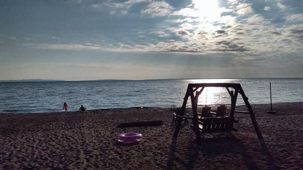 Ein Strand mit einer Schaukel, einer Bank und einem Frisbee im Sand.