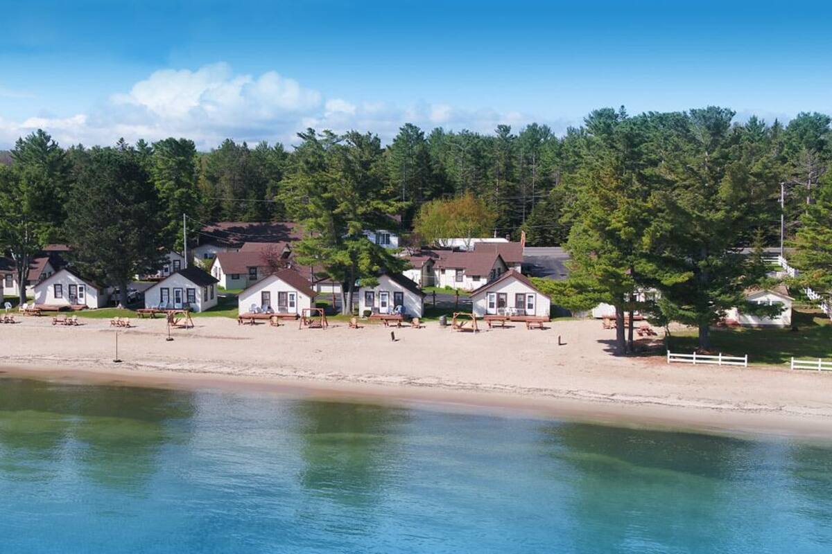 A beachfront property with multiple white houses, a sandy beach, and a calm body of water.