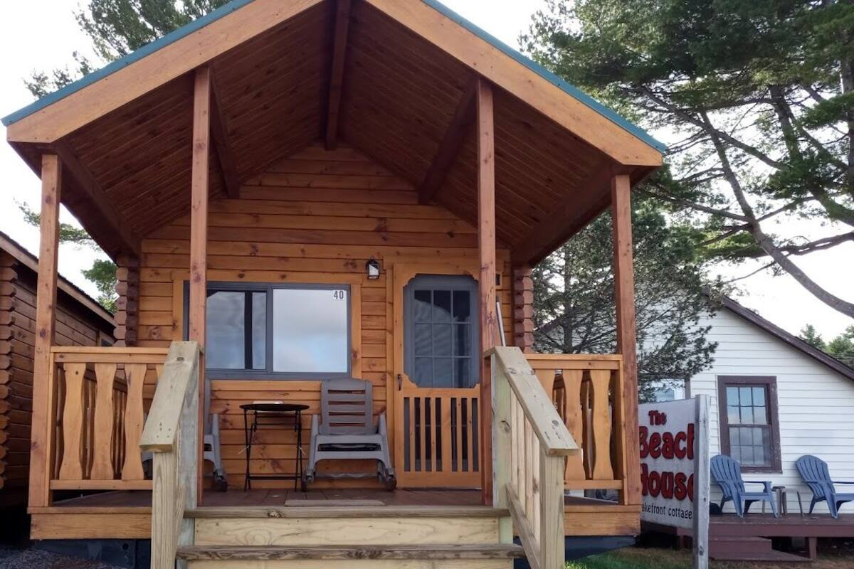 A wooden cabin with a porch, a table, and two chairs.